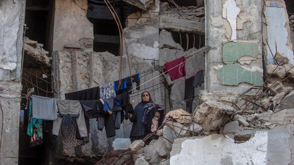 Palestinka skuplja veš koji visi unutar uništene zgrade u gradu Gazi