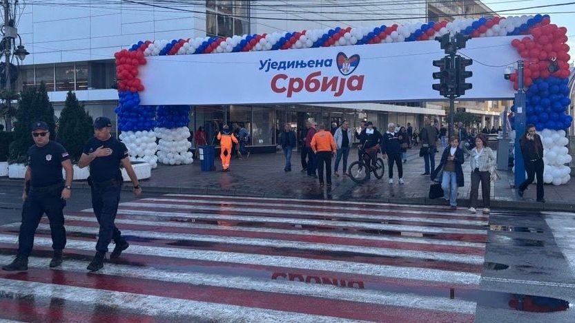 Dva policajca prelaze ulicu, baloni u bojama zastave Srbije