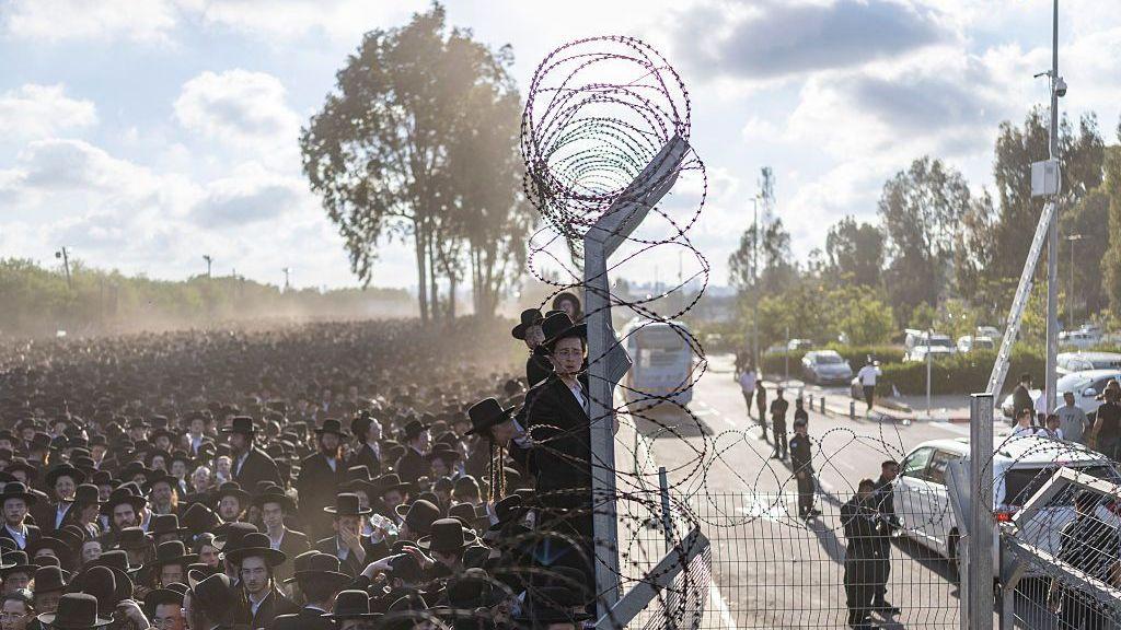 Stotine ili hiljade ultraortodoksnih Jevreja stoje pored bodljikave žice
